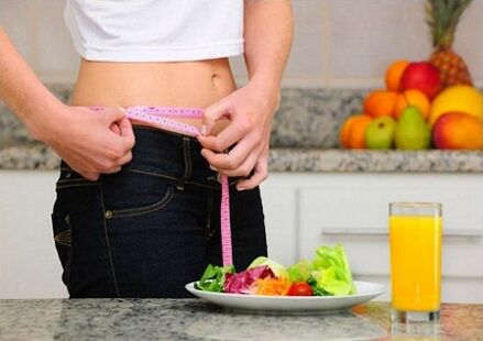 A girl losing weight on a diet measures her waist size